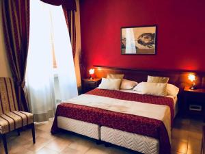 a bedroom with a large bed with a red wall at Hotel Borgo Antico in Fabriano