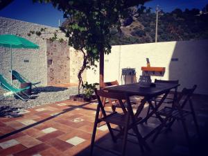 米拉佐Dimora d'Estate (Sicilian Holidays)的露台上摆放着一张桌子和几把椅子，露台上有一棵树