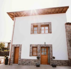 a white house with brown doors and windows at El Riveru - Astur Casas Rurales in Balmori