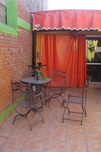 einen Tisch und Stühle auf einer Terrasse mit einem roten Vorhang in der Unterkunft Intiaconcagua Habitaciones Familiares in Ciudad Lujan de Cuyo