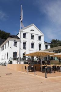 ein weißes Gebäude mit Tischen und Sonnenschirmen davor in der Unterkunft Hotel Kieler Yacht-Club in Kiel