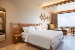 a bedroom with a large white bed and a living room at Centara Korat in Nakhon Ratchasima