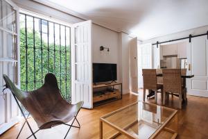 sala de estar con mesa de cristal y silla en Magno Apartments Vidrio, en Sevilla
