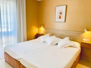 1 dormitorio con 1 cama grande con almohadas blancas en Hotel Venteo, en Platja d'Aro