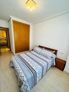 Schlafzimmer mit einem Bett mit einer blauen und weißen Bettdecke in der Unterkunft Costa Caribe II Nº 1028 in Oropesa del Mar