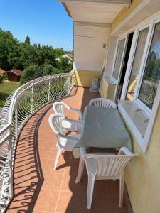 a balcony with a table and chairs on a house at Esther Apartman in Gyenesdiás