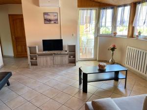 a living room with a couch and a tv at Esther Apartman in Gyenesdiás