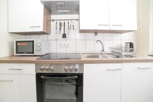 een keuken met witte kasten, een fornuis en een wastafel bij Othman Appartements Anderter Straße 55a 1OG in Hannover