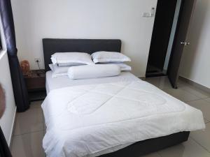 Una cama con sábanas blancas y almohadas. en Heritage Homestay en Kota Tinggi