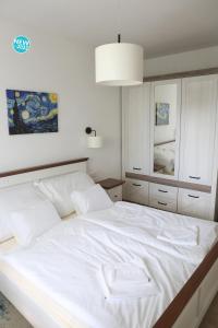 una camera da letto con un grande letto bianco e uno specchio di St.Gotthard Apartman a Szentgotthárd