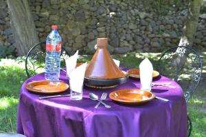 a purple table with plates and a bottle of water at Auberge De La Vallée in Imlil