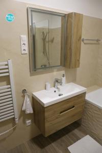 e bagno con lavandino, specchio e vasca. di St.Gotthard Apartman a Szentgotthárd