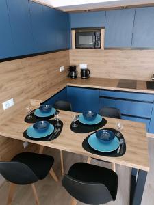 - une table en bois avec des assiettes et des verres dans la cuisine dans l'établissement Apartament Claudia, à Darłówko