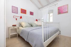 a white bedroom with a white bed and a table at House Encanto in Veli Lošinj