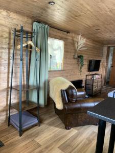 a living room with a leather couch and a shelf at 1 bedroom woodland cabin in Launceston