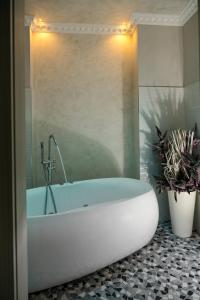 波隆那的住宿－Albergo Rossini 1936，浴室内有白色的浴缸,种植了两株盆栽植物