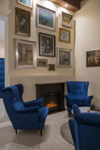 a living room with blue chairs and a fireplace at Albergo Rossini 1936 in Bologna