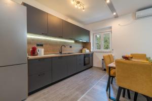 uma cozinha com armários cinzentos, uma mesa e uma mesa; em Apartman Galeb em Trogir