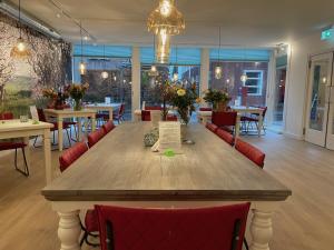 een grote houten tafel in een restaurant met rode stoelen bij Cozy Bed and Breakfast in Elst