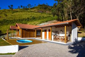 a house on a hill with a patio at Recanto Águas Nascentes - Casa na serra com piscina e cachoeira no quintal!! in Pedra Menina