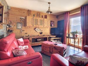 a living room with a red couch and a tv at Chalet les Fiz in Passy