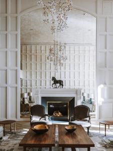 a living room with a fireplace and a chandelier at Royal Champagne Hotel & Spa in Champillon