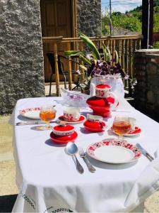a table with red and white plates and silverware on it at Guest house Babaka in Sighnaghi