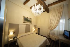 1 dormitorio con cama y lámpara de araña en Albergo Rossini 1936 en Bolonia