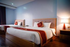 a hotel room with two beds and a lamp at Phoenix3 Hotel Bắc ninh in Bắc Ninh