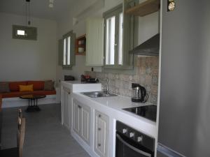 a kitchen with white cabinets and a sink and a couch at Magma & Tefra in Éxo Goniá