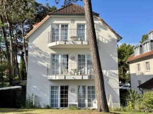 Una casa blanca con un árbol delante. en Haus Kiek Ut Apartment 23, en Timmendorfer Strand