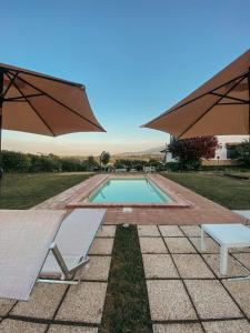 a swimming pool with two chairs and two umbrellas at Bed & Breakfast Le Coccinelle in Rosciano