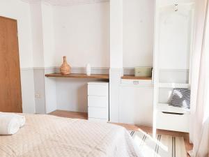 a white bedroom with a bed and a shelf at Gästehaus an der Moseltherme in Traben-Trarbach
