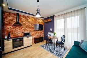 a kitchen and living room with a brick wall at Apartament ,, COŚ NIECOŚ ,, Suwałki LOFT, KLIMATYZACJA,GARAŻ, ŁADOWANIE AUT ELEKTRYCZNYCH, MONITOROWANE ZAMKNIĘTE OSIEDLE in Suwałki