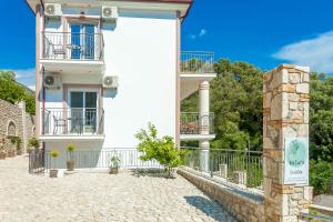 a white building with balconies and a gate at Natura Luxury Suites Parga in Parga
