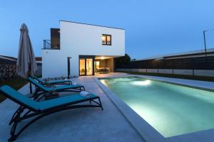 a swimming pool with two lounge chairs and a house at Modern 3-bedroom villa with a private pool in Pula