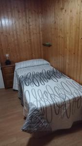 a bed in a room with a wooden wall at Piso centrico en Pravia, con 3 habitaciones sin ascensor in Pravia