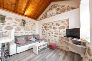 uma sala de estar com um sofá e uma televisão em Little stone house em Buići