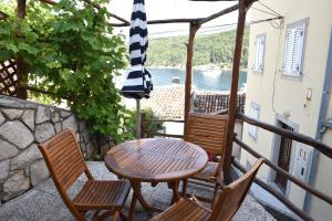 a patio with a table and chairs and an umbrella at Apartment Anamarija Valun in Valun
