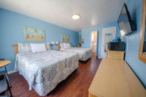 Cette chambre bleue comprend 2 lits et une télévision. dans l'établissement Surfcomber Motel, à Wildwood