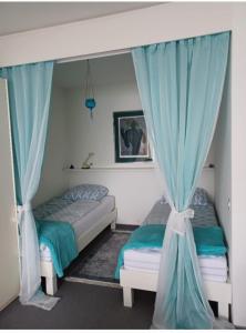 two beds in a bedroom with blue curtains at Sollevante Ascona in Ascona