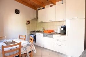 a kitchen with white cabinets and a table and a table and chairs at Apartment Anamarija Valun in Valun