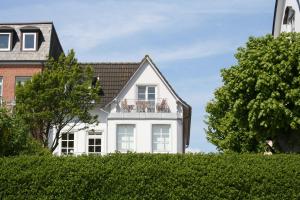 ein weißes Haus mit Balkon auf einer Hecke in der Unterkunft Sandwallkoje in Wyk auf Föhr