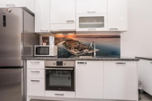 a kitchen with white cabinets and a pan of food at Apartments Maza in Zadar