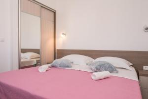 un grande letto con due cuscini e uno specchio di Apartments Maza a Zara (Zadar)