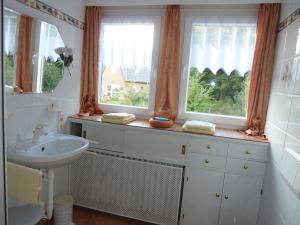 a bathroom with a sink and two windows at Gästehaus Villa Kreativ Susanne Lay in Bad Münder am Deister +17 photos
