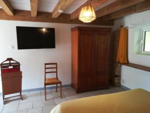 une chambre avec une télévision au mur et une chaise dans l'établissement LE POTAGER, à Monclard