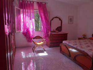 カルデードゥにあるVilletta Immersa Nella Naturaのピンクのカーテン、ベッド、鏡が備わるベッドルーム1室が備わります。