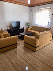 sala de estar con sofás y TV de pantalla plana. en Villa Ideal, en Ksamil