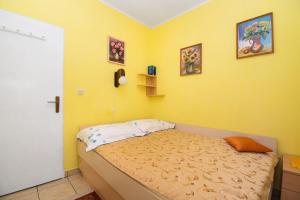 a bedroom with a bed with a yellow wall at Apartments Danica in Murter